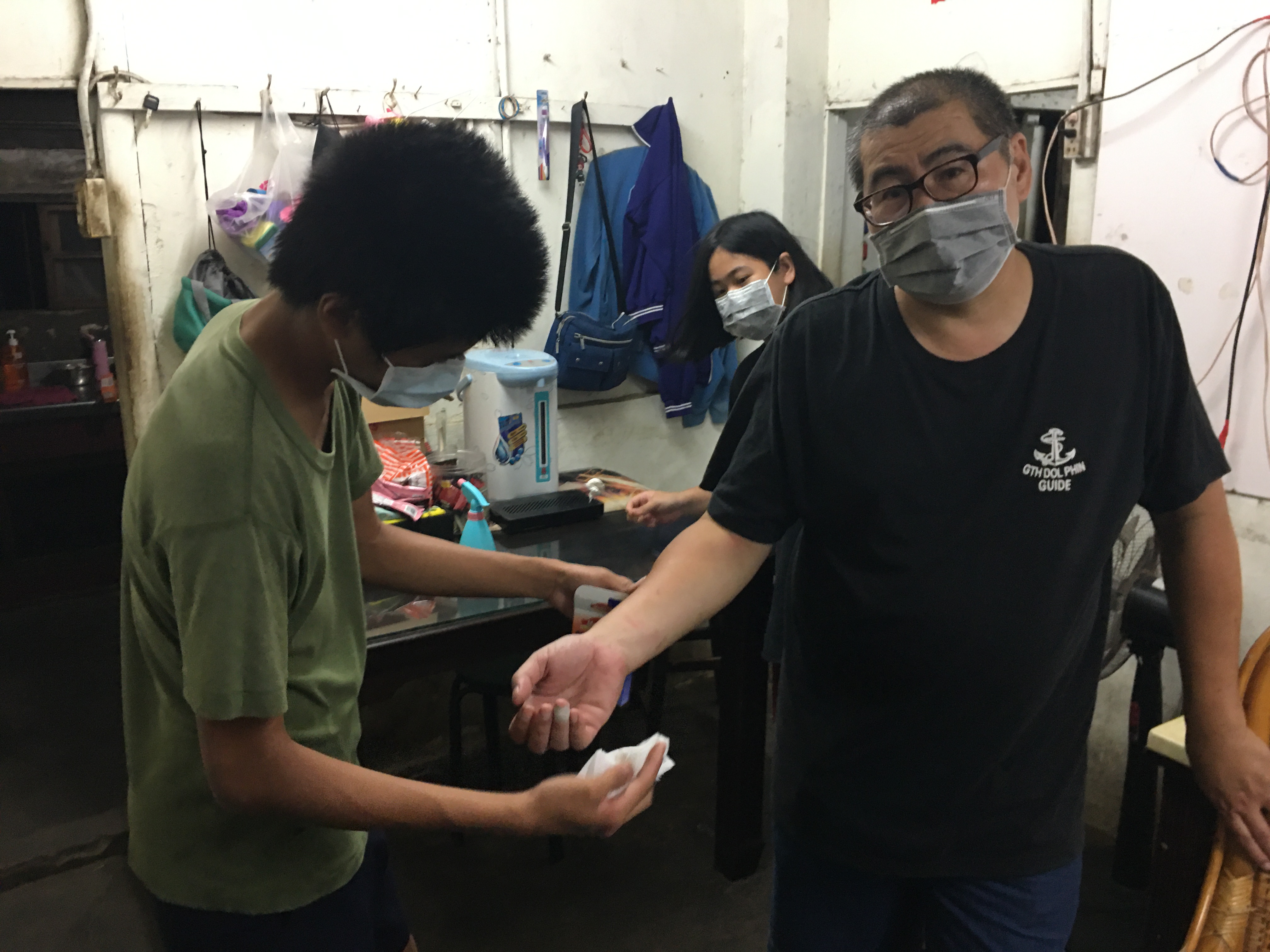 鍾志春(右一)被發脾氣的智障長女抓傷手臂,讀國二長子幫他擦藥。向高彬攝 鍾志春(右一)被發脾氣的智障長女抓傷手臂,讀國二長子幫他擦藥。向高彬攝
