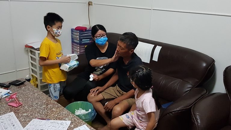 阿亭(左2)幫罹4期口腔癌的先生阿淵(右2)放療傷口擦藥,一旁為年幼子女小仁(左1)、小靜。韓旭爾攝 阿亭(左2)幫罹4期口腔癌的先生阿淵(右2)放療傷口擦藥,一旁為年幼子女小仁(左1)、小靜。韓旭爾攝