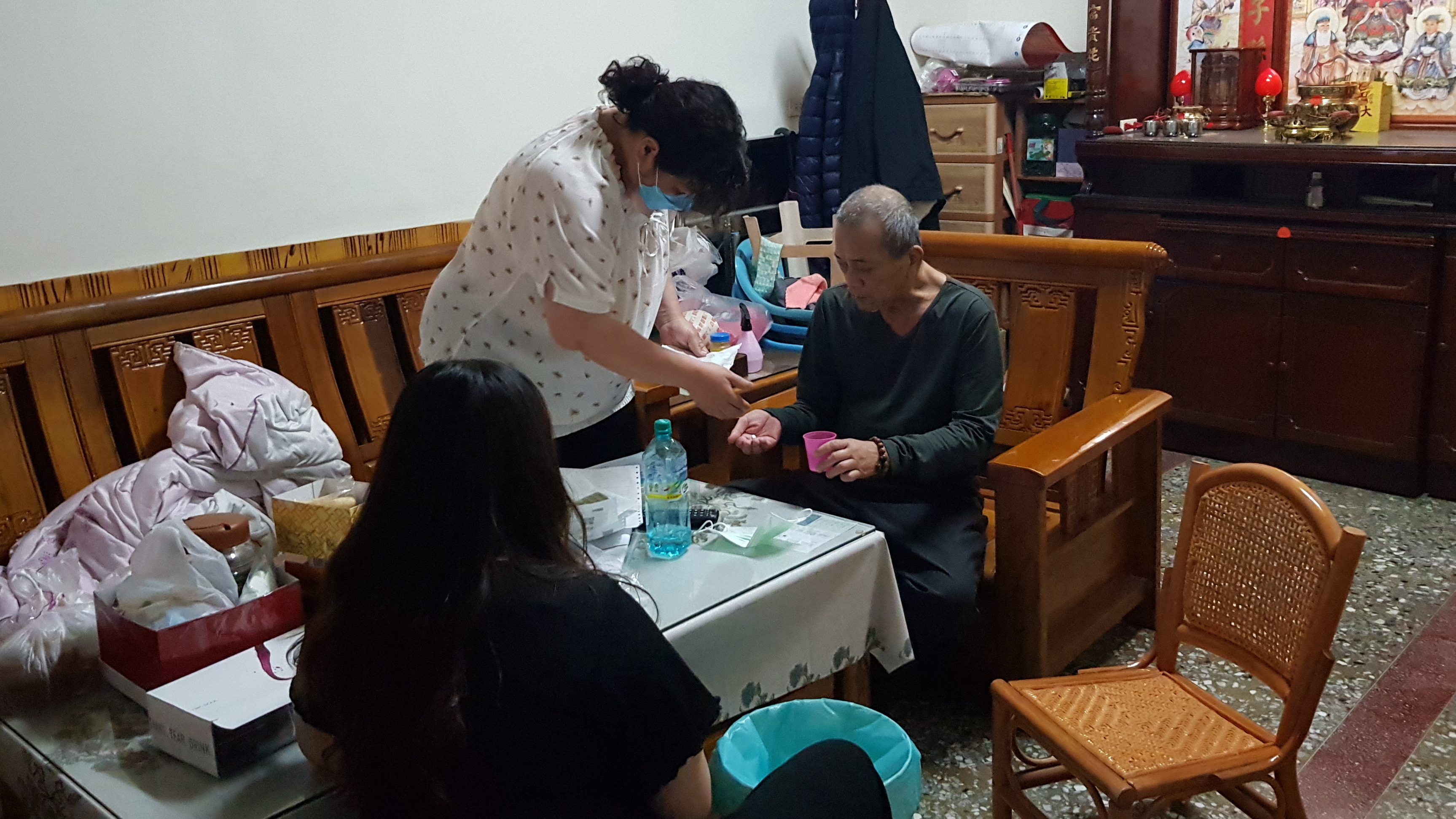 阿珍(後左)照料罹患3期肺癌的先生阿凱(後右)服藥,一旁為讀大一女兒小雯。韓旭爾攝 阿珍(後左)照料罹患3期肺癌的先生阿凱(後右)服藥,一旁為讀大一女兒小雯。韓旭爾攝
