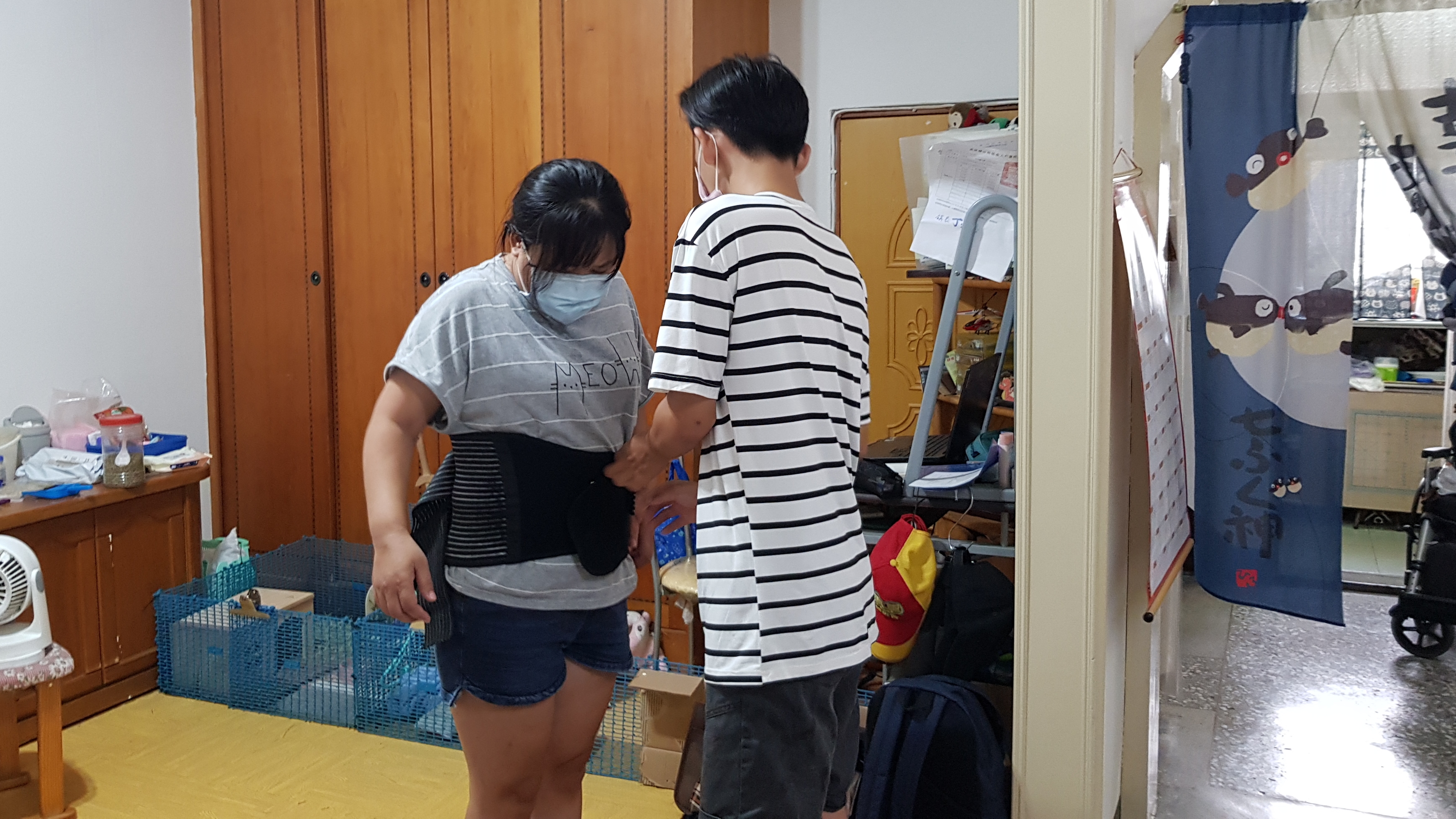 阿梅(左)因長期照顧臥床婆婆,脊椎受傷,次子小斌幫忙穿上護腰固定。韓旭爾攝 阿梅(左)因長期照顧臥床婆婆,脊椎受傷,次子小斌幫忙穿上護腰固定。韓旭爾攝